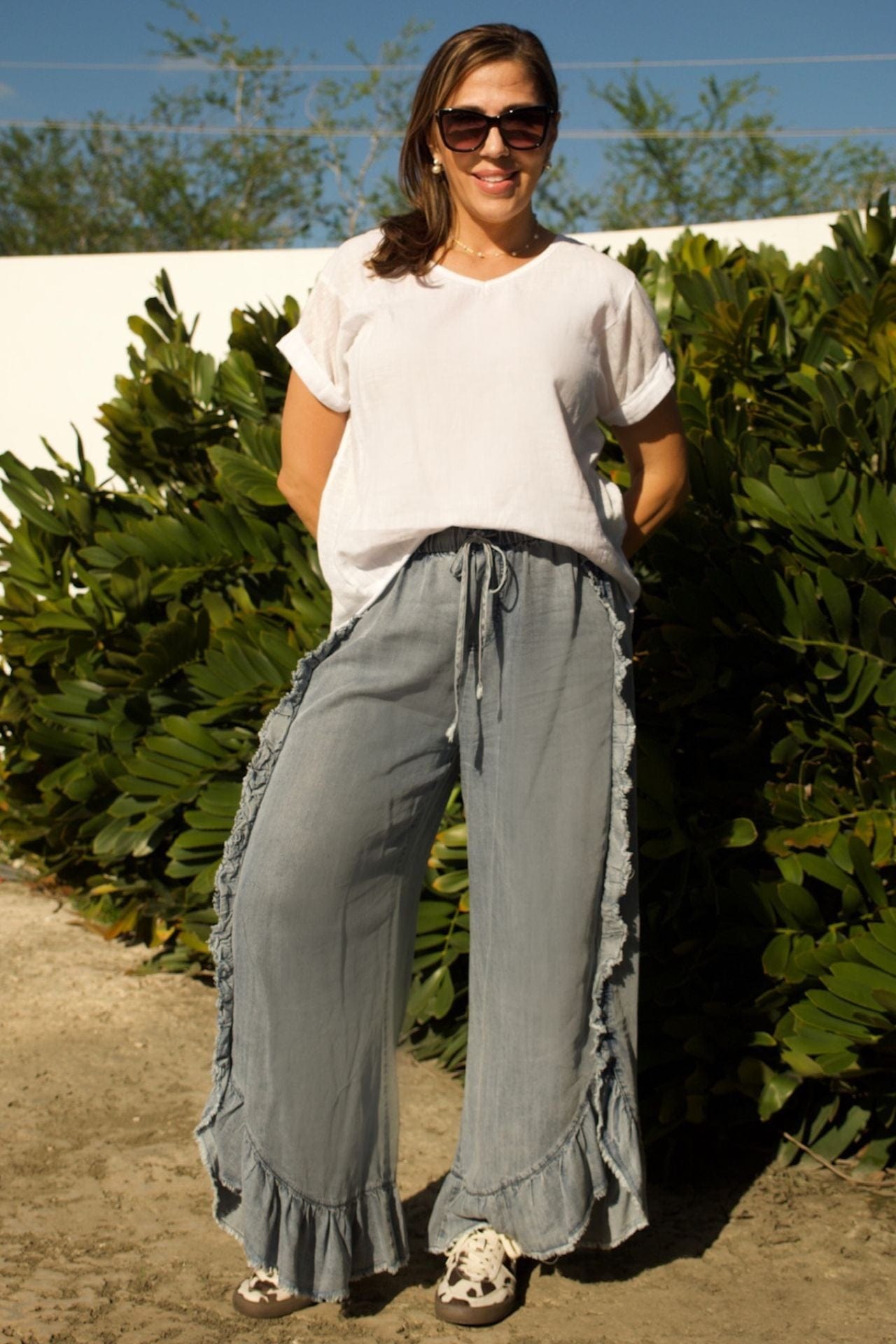 Front view of womenâs denim ruffled pants and white linen high-low V-neck tee set