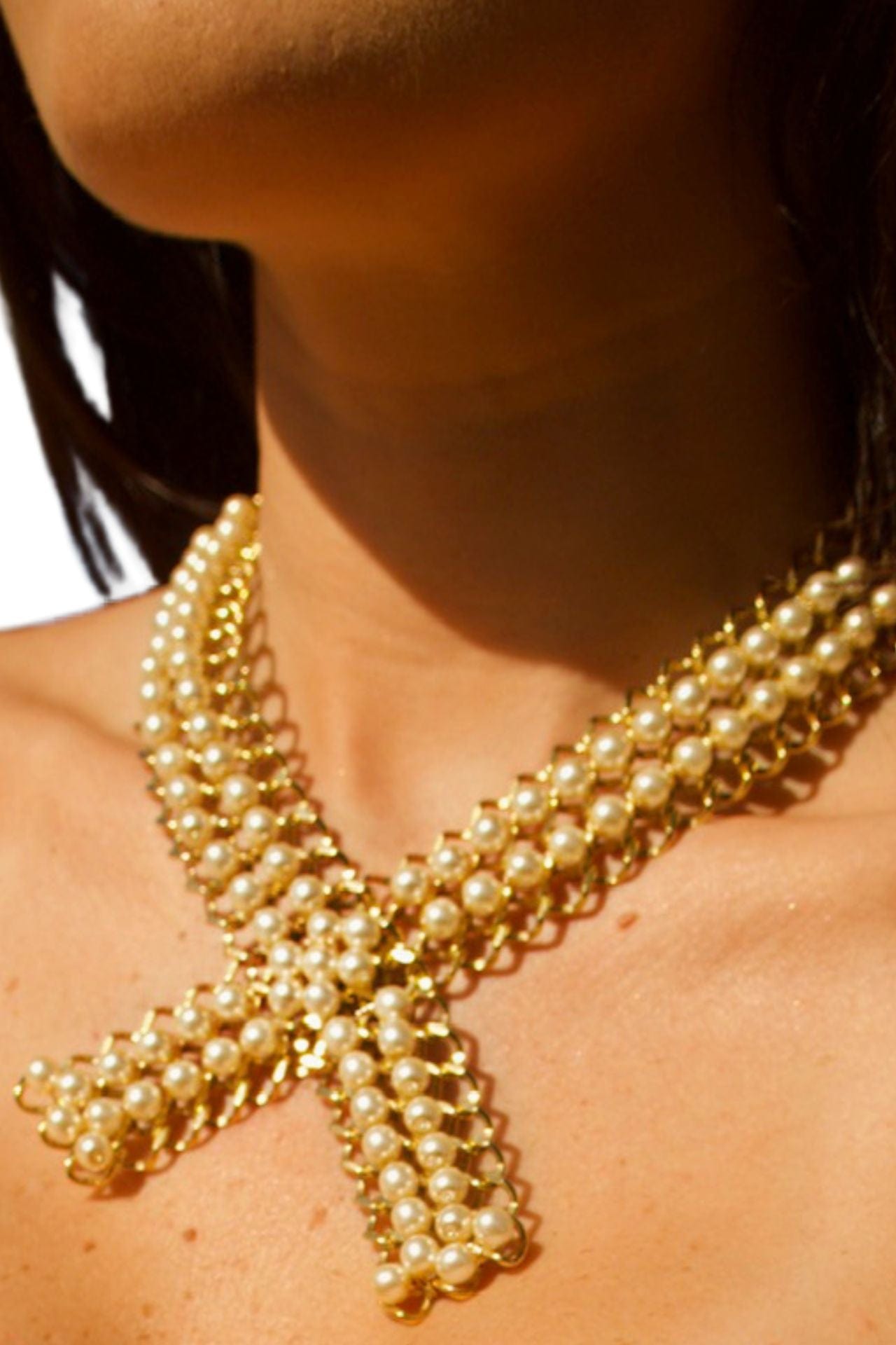 Gold brass necklace with X-shape and pearl accents worn by model — handmade and 22k gold-coated