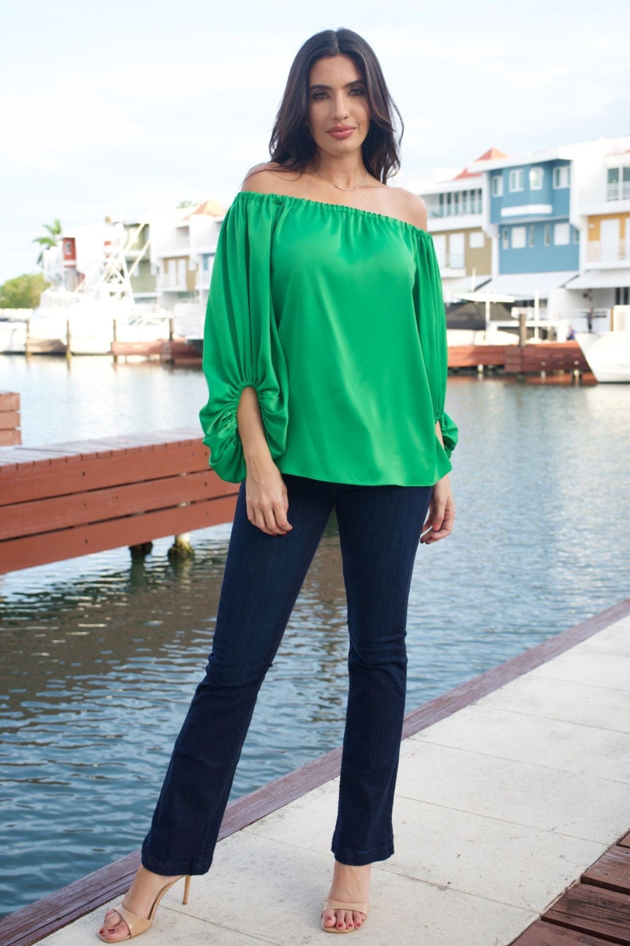 Woman wearing emerald green off-the-shoulder top with balloon sleeves, front view.