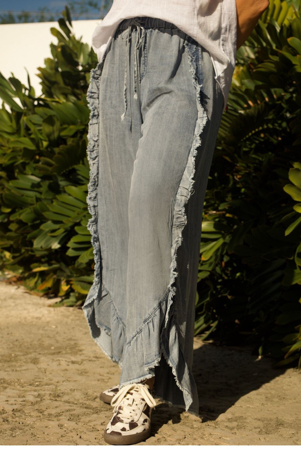 Close-up of ruffle detail on denim pants and linen texture of V-neck top