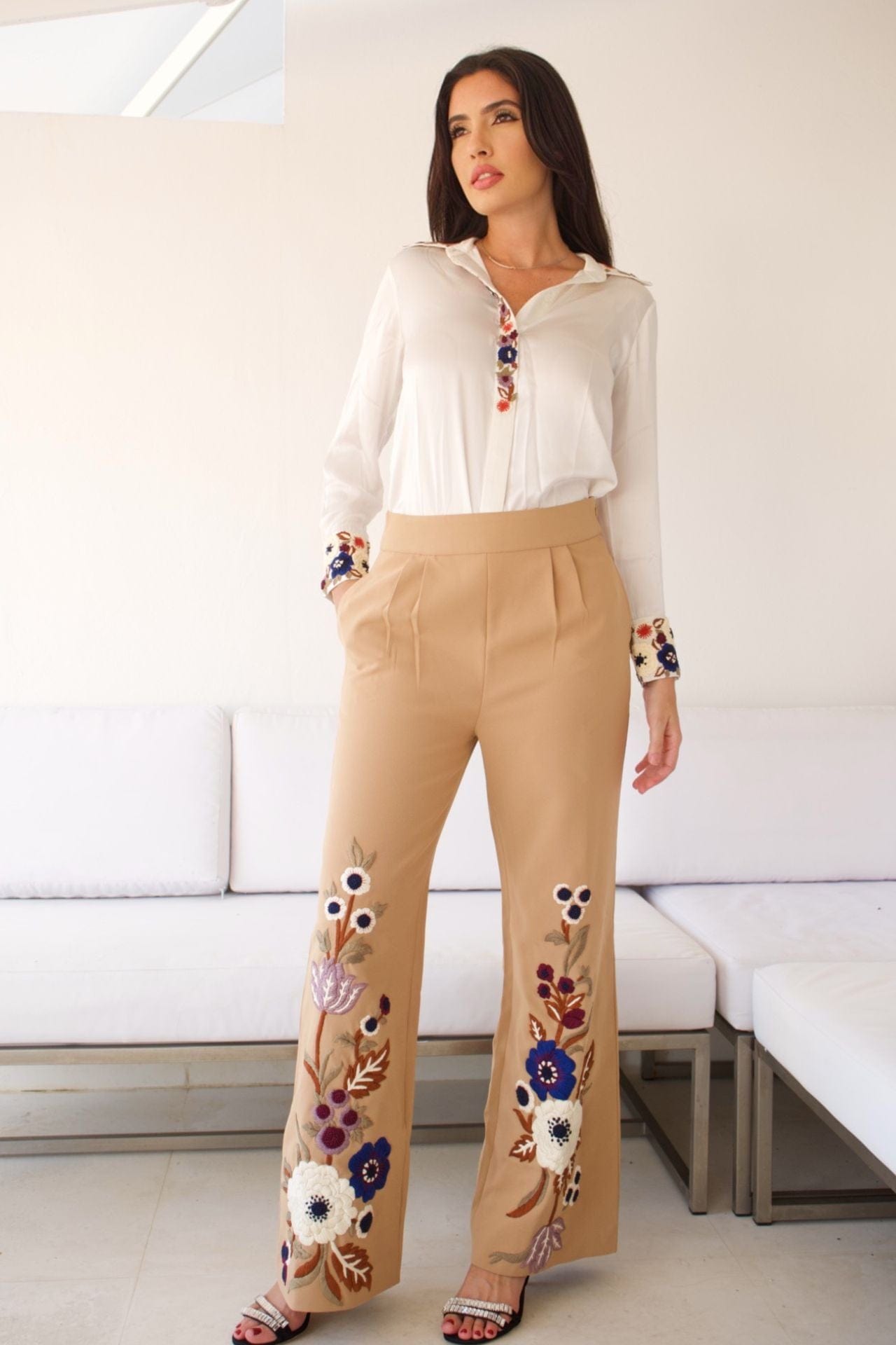 Woman wearing beige pant set with floral embroidery and white blouse, standing confidently.