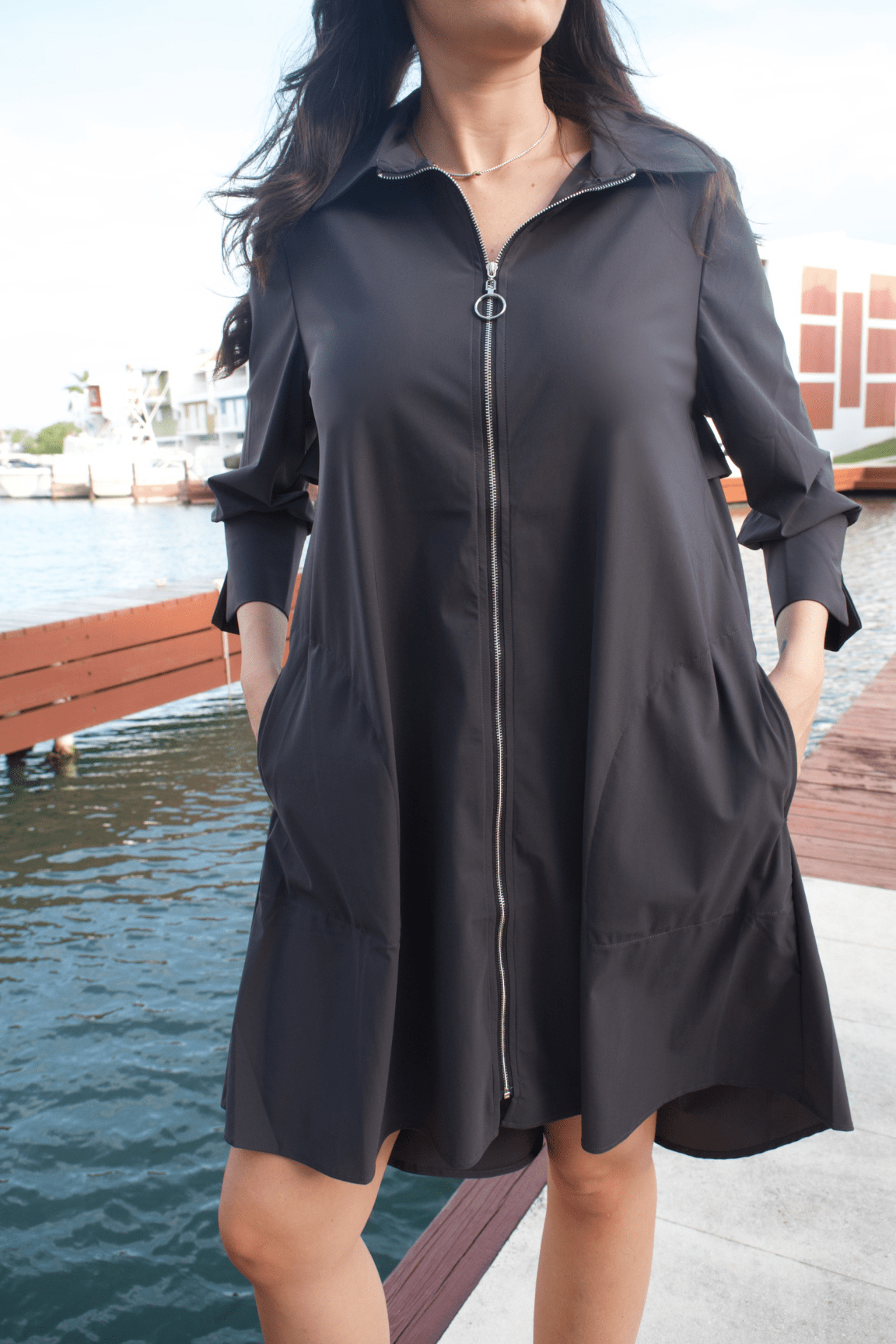 Close-up detail of the women's zip-up knee-length charcoal dress jacket, highlighting the fine fabric texture and zipper detail for an elegant touch.