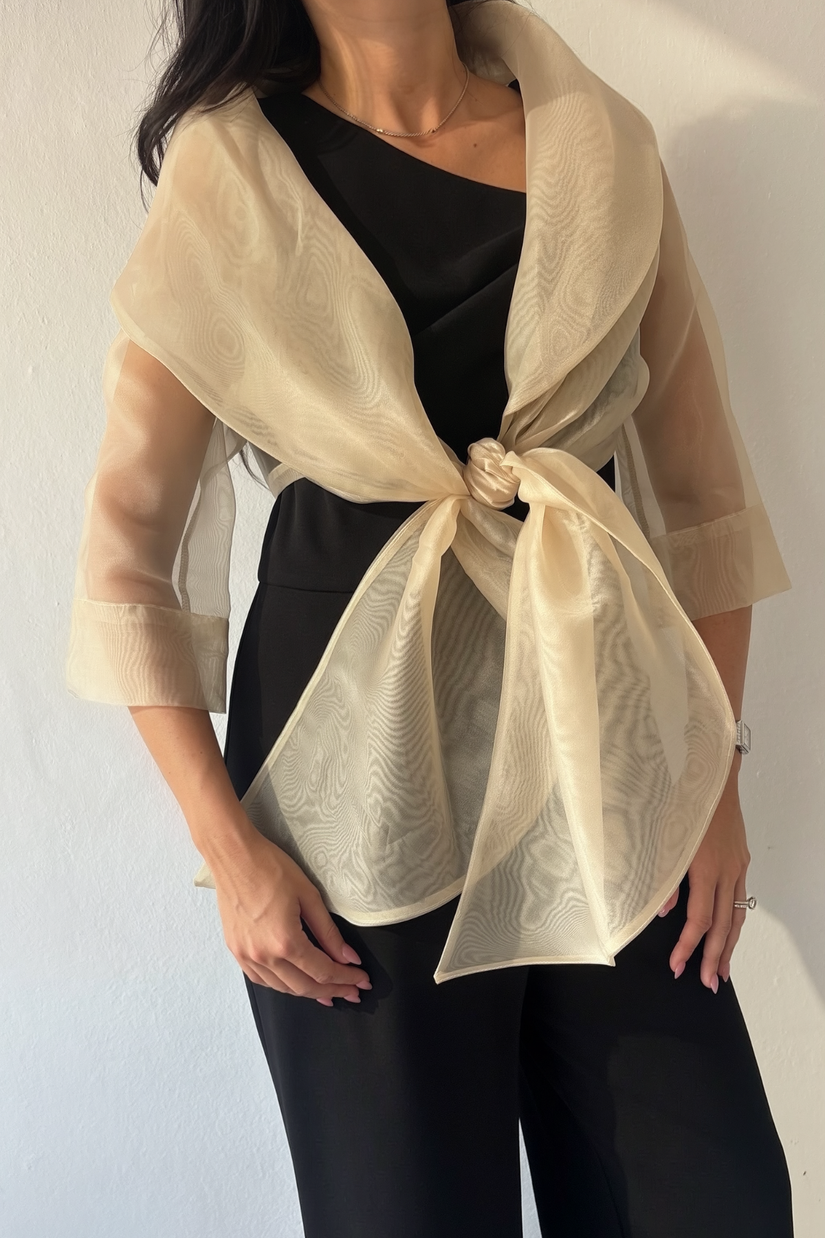 Sheer gold organza wrap with oversized collar and tie front styled over black jumpsuit