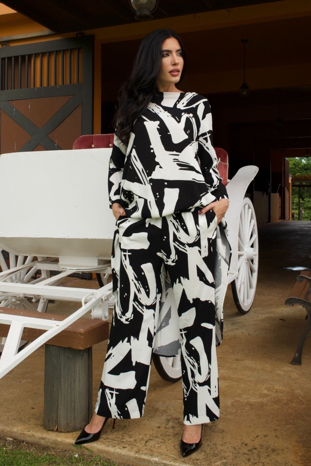 Woman wearing black and white abstract print high-low tunic set with matching wide-leg pants-front view.