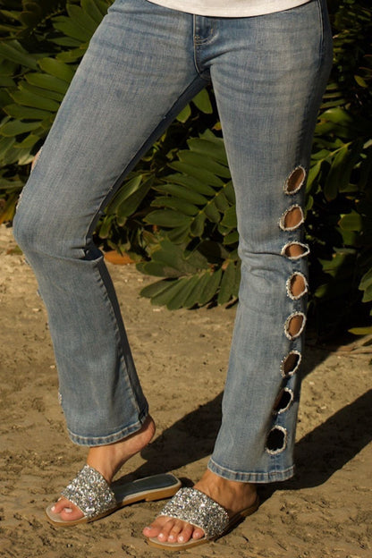 Close-up of rhinestone-trimmed circular cutouts on side of denim pant leg