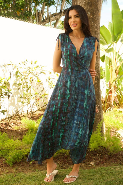 Woman wearing navy and turquoise printed sleeveless wrap maxi dress with V-neckline.

