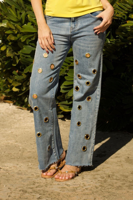 Close-up of grommet trim detail on light blue denim fabric.