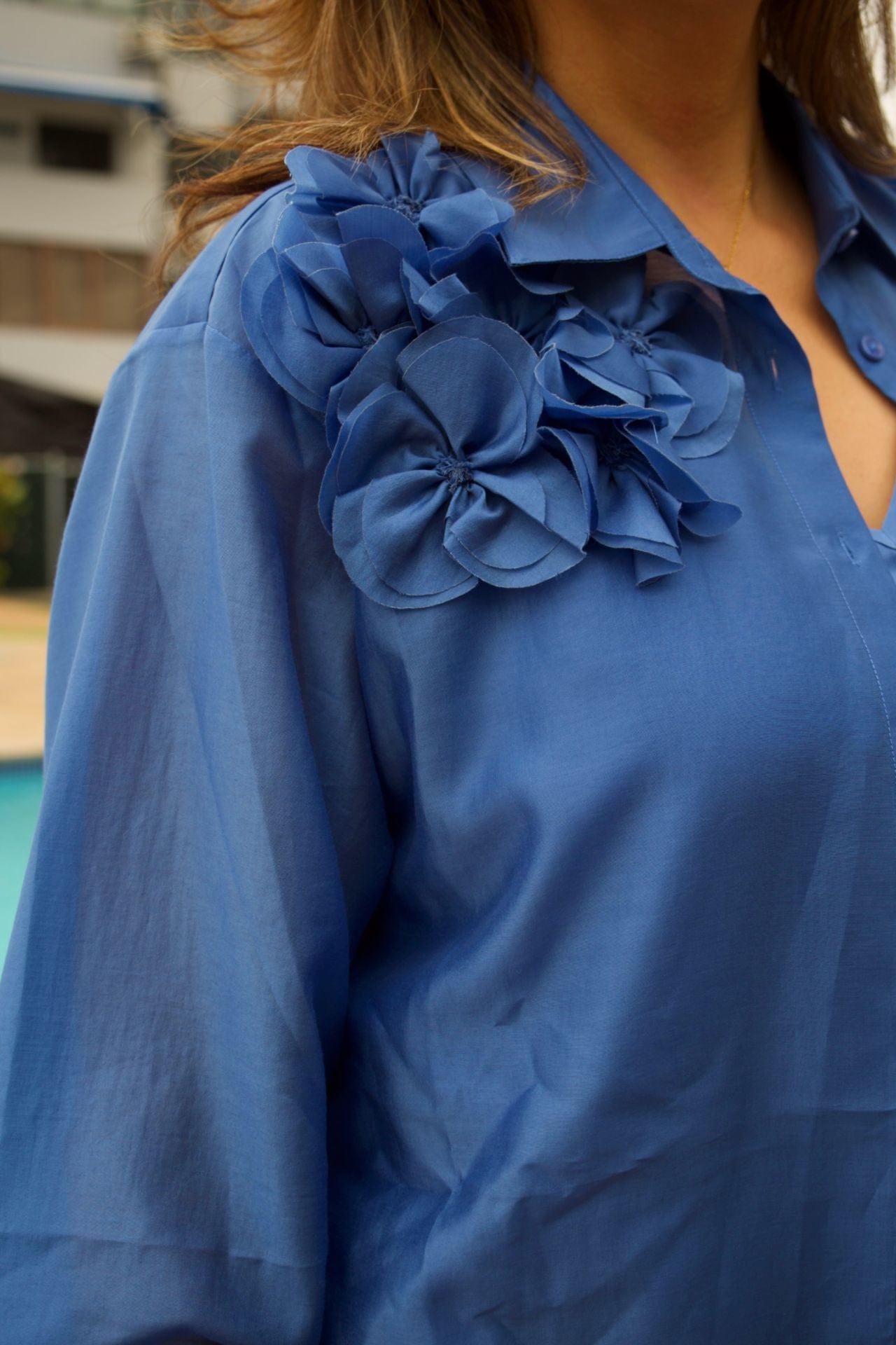 Blue satin shirt with floral detail on shoulder – elegant and feminine blouse with sheen finish-close up

