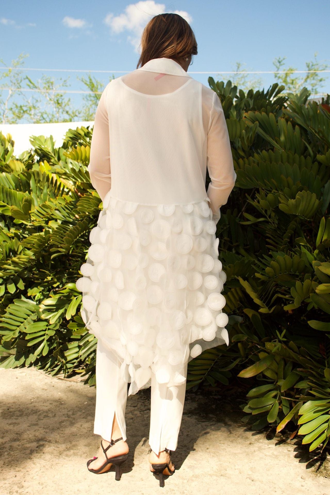 Back view of women's white high-low mesh blouse showing high-low hemline and mesh texture.