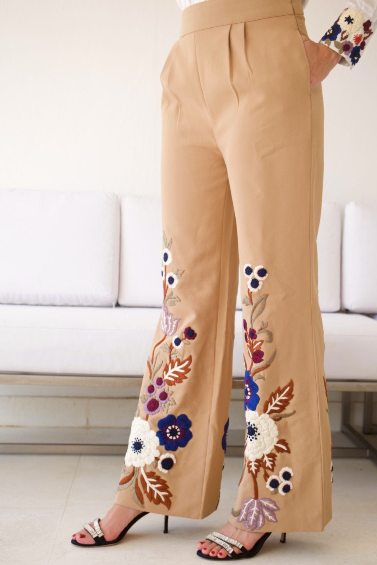 Close-up of floral embroidery on beige pants and cuff detail on blouse.

