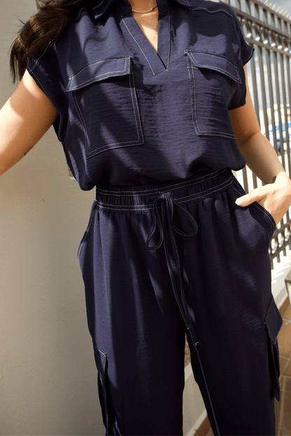 Detailed view of white stitch accents on a women's navy cargo pant set, highlighting its modern and refined design.