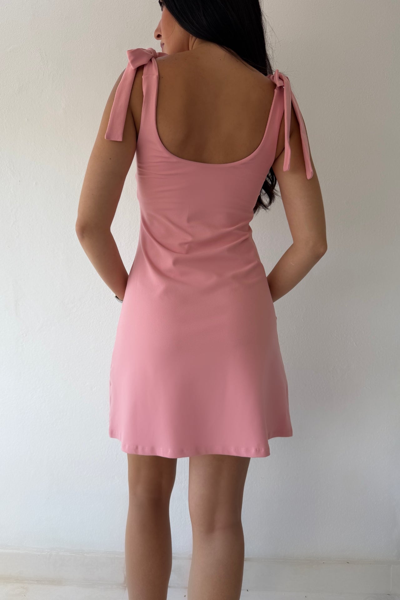 Model wearing the Blush Breeze Dress in soft blush pink featuring tie shoulder straps and a flattering A-line silhouette.