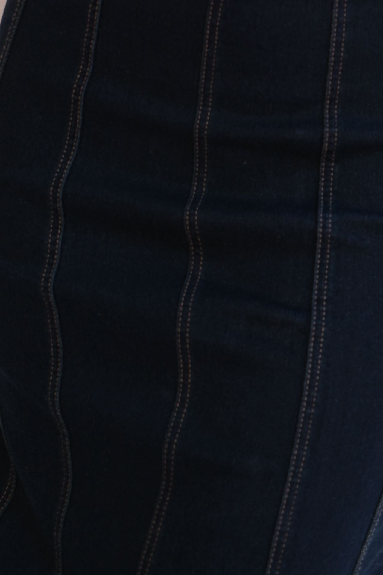 Close-up of dark blue fabric with beige stitching
