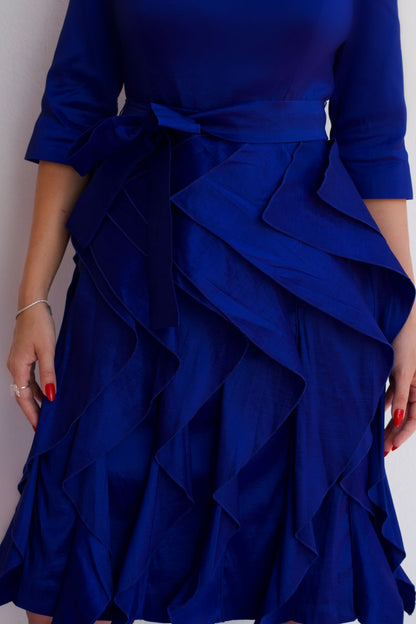 Close up royal blue taffeta dress with waist tie and ruffle skirt, styled for an elegant cocktail or special occasion look