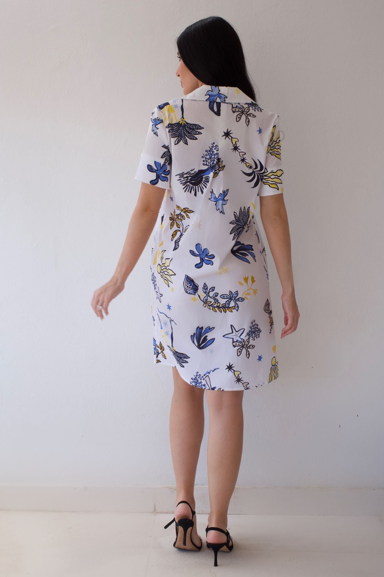 Woman wearing a coastal sketch dress against a white background. 