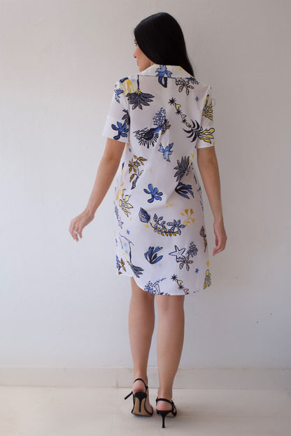 Woman wearing a coastal sketch dress against a white background. 