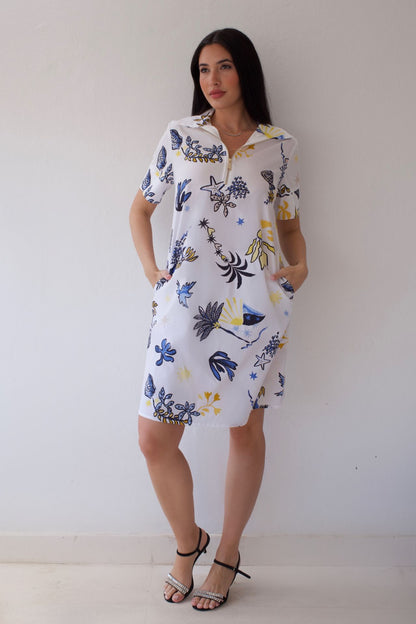 Woman wearing a white dress with colorful floral pattern against a plain background