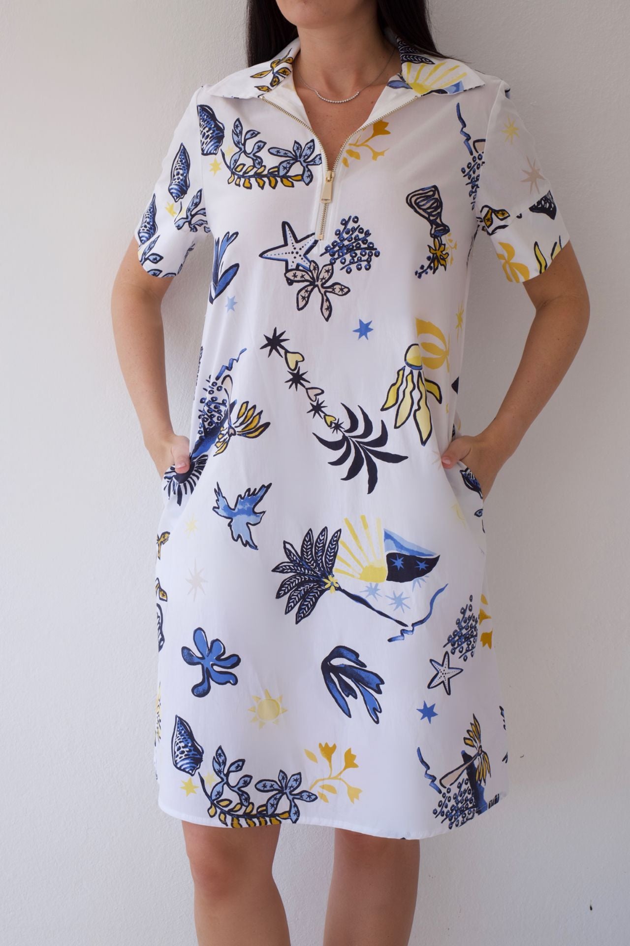Woman wearing a white dress with coastal sketch pattern against a plain background