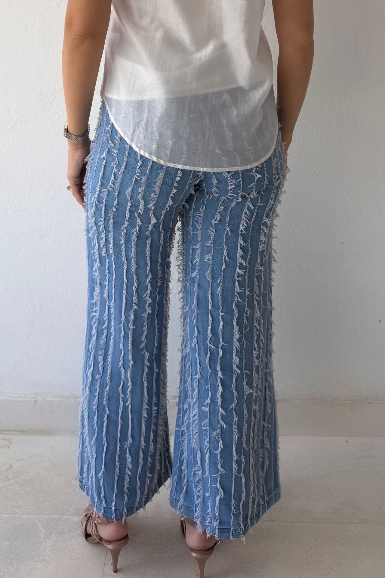 Model wearing textured wide-leg statement denim pants paired with a white statement blouse.