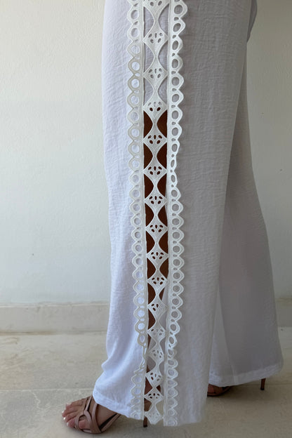 Model wearing the Island Breeze Pant Set featuring a white long sleeve blouse with decorative cutout trim and coordinating wide-leg pants.
