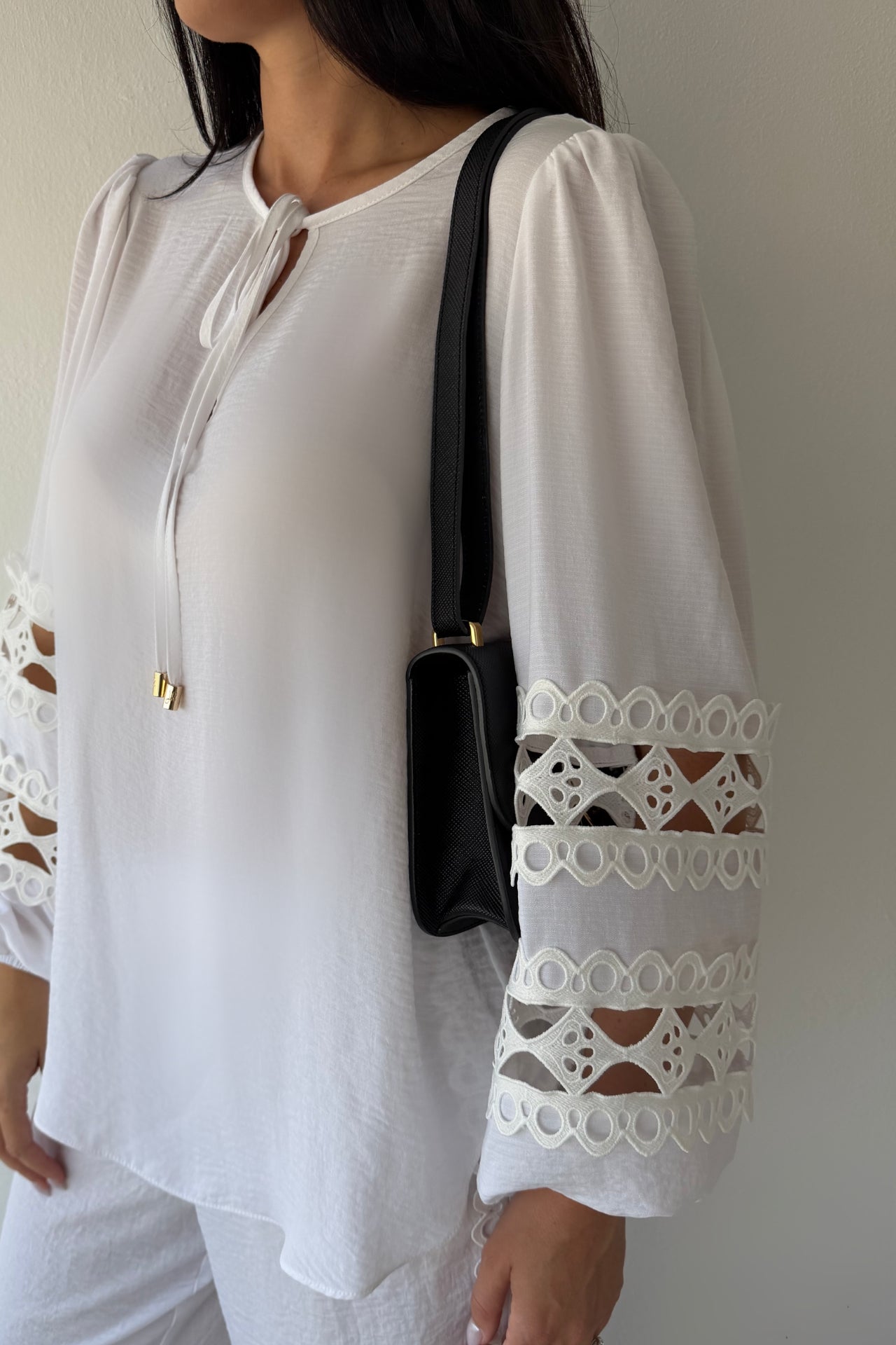 Model wearing the Island Breeze Pant Set featuring a white long sleeve blouse with decorative cutout trim and coordinating wide-leg pants.