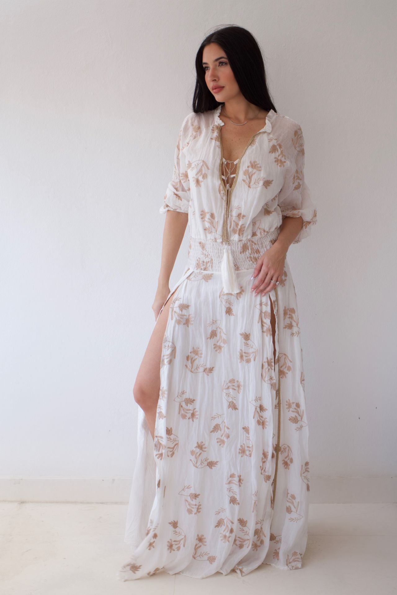 Woman wearing a white floral dress against a plain background