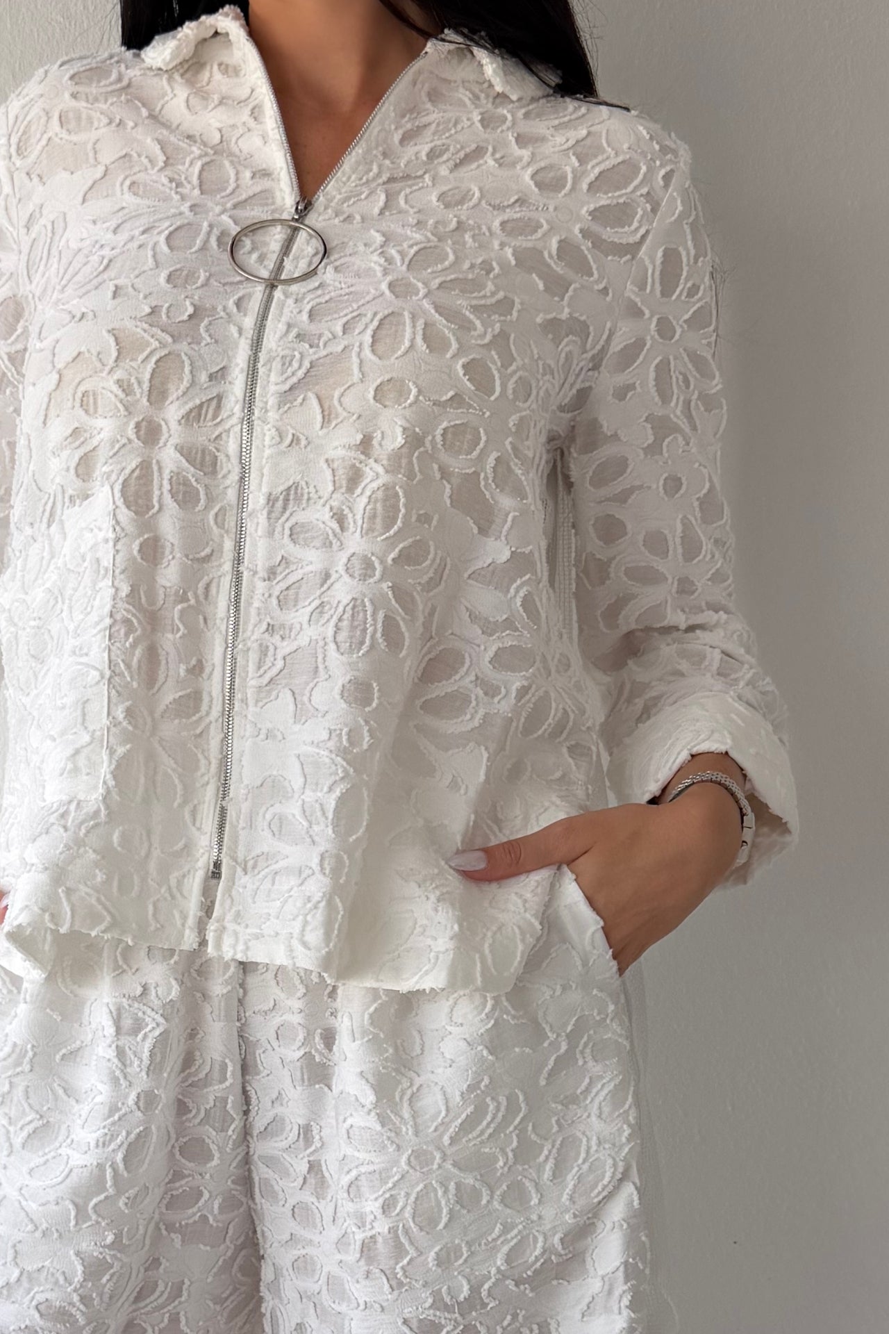 Model wearing the Ivory Garden Texture Set featuring a textured floral zip-front jacket and matching wide-leg pants in ivory.