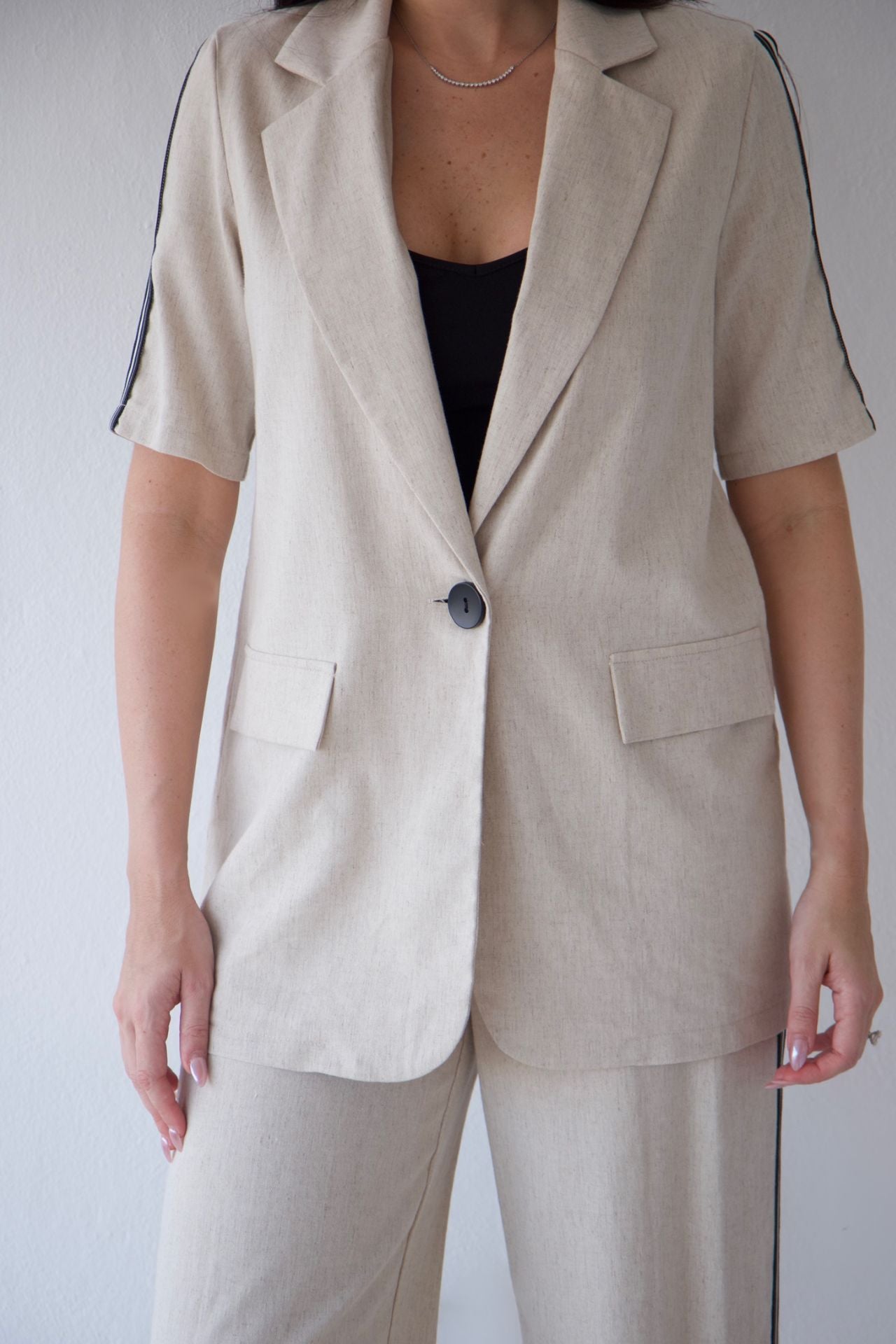 Person wearing a beige suit with a plain background