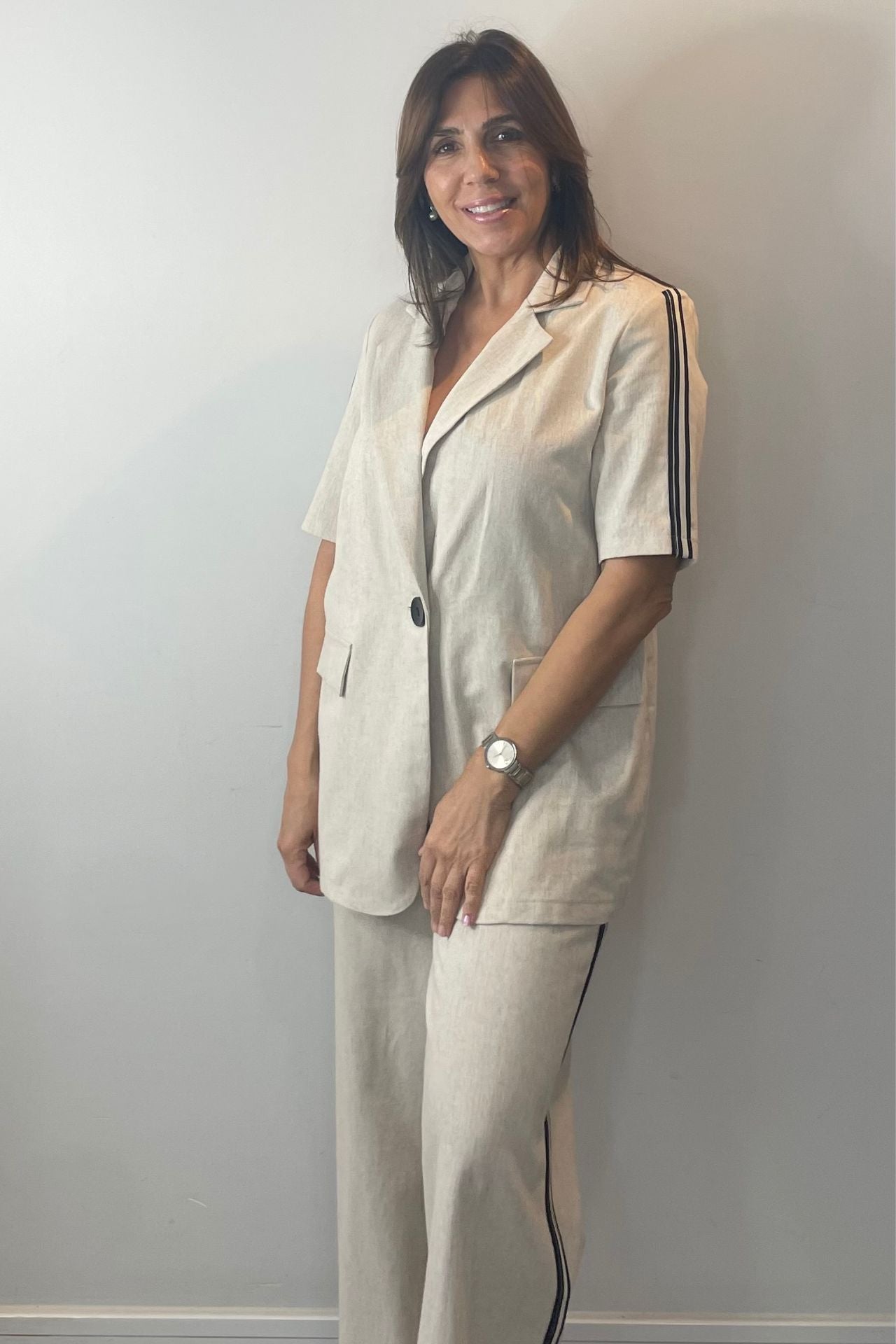 Woman wearing a beige outfit with black stripes against a plain background