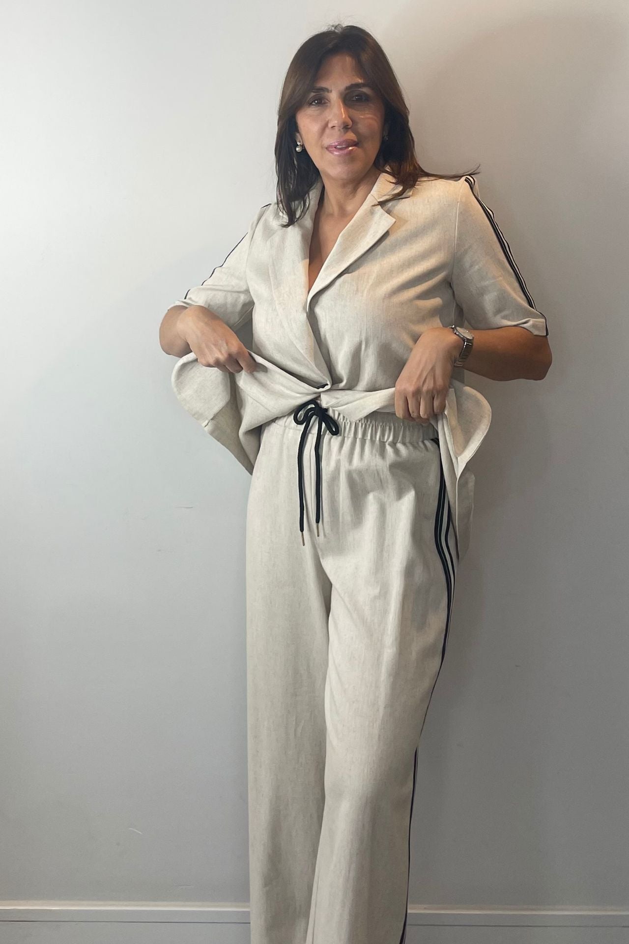 Woman wearing a beige jumpsuit against a plain wall