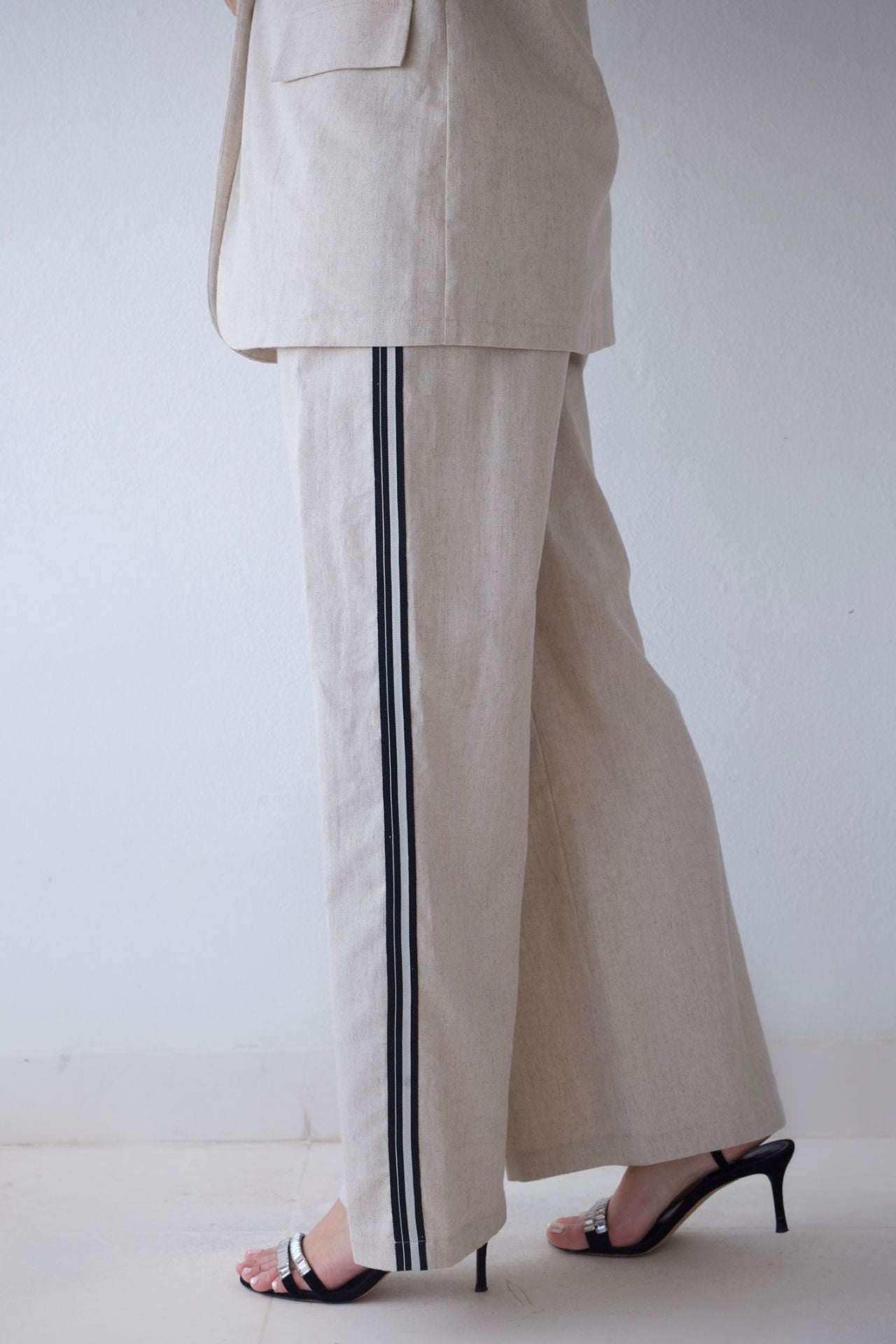 Beige pants with black stripes worn by a person on a white background