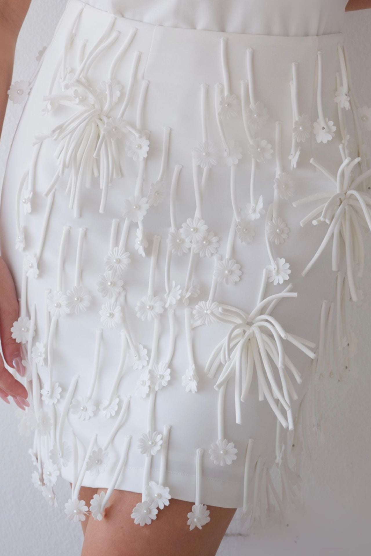 White skirt with 3D floral  apliqué on a plain background