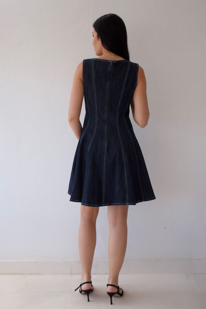 Woman wearing a dark denim sleeveless dress against a plain background