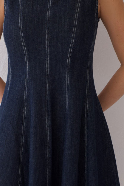 Dark blue denim dress with white stitching on a neutral background