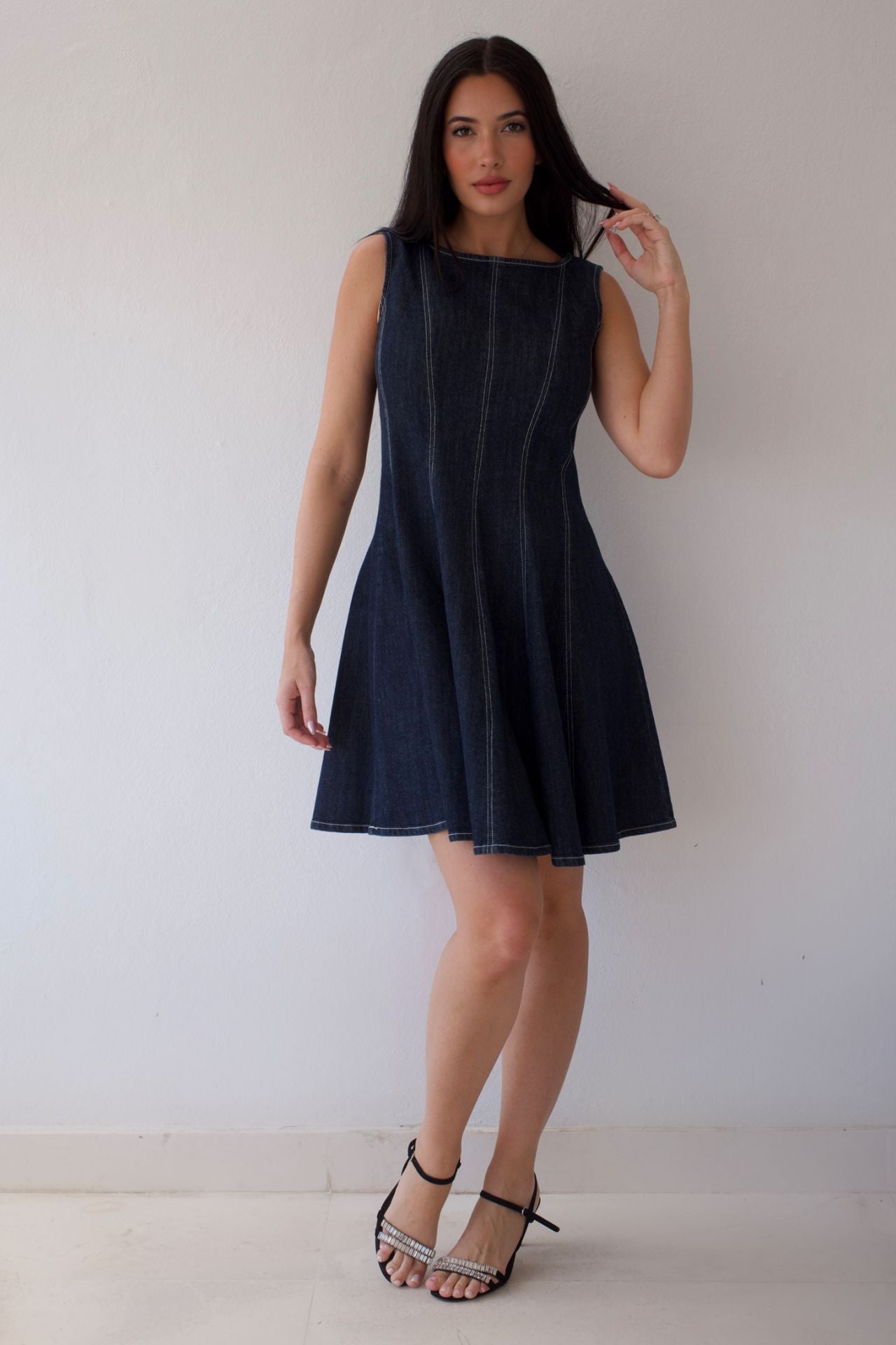 Woman wearing a dark denim sleeveless dress against a plain background