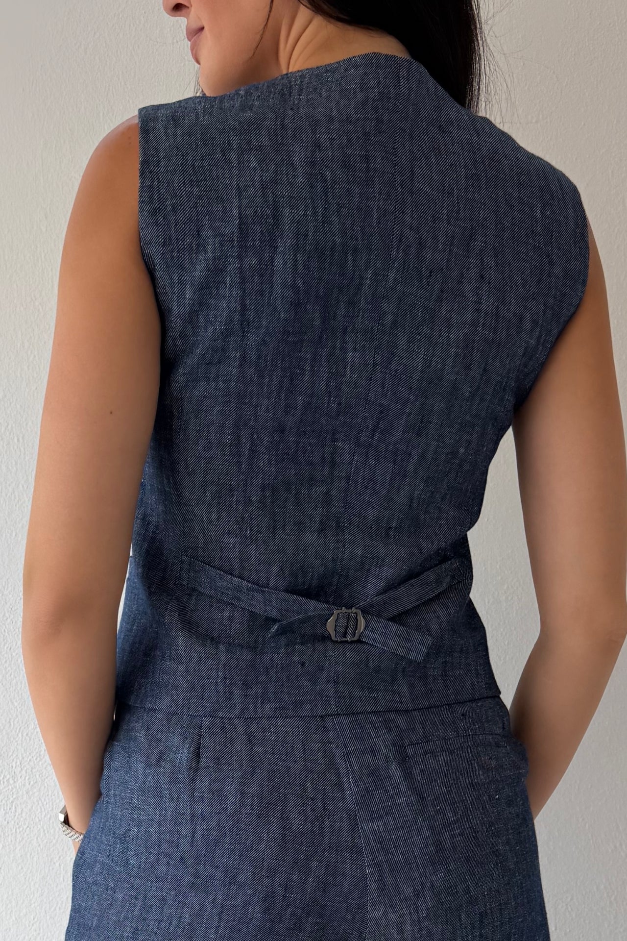 Model wearing the Midnight Tailored Vest in navy linen featuring a sleeveless tailored silhouette, front button closure, and adjustable back buckle detail.