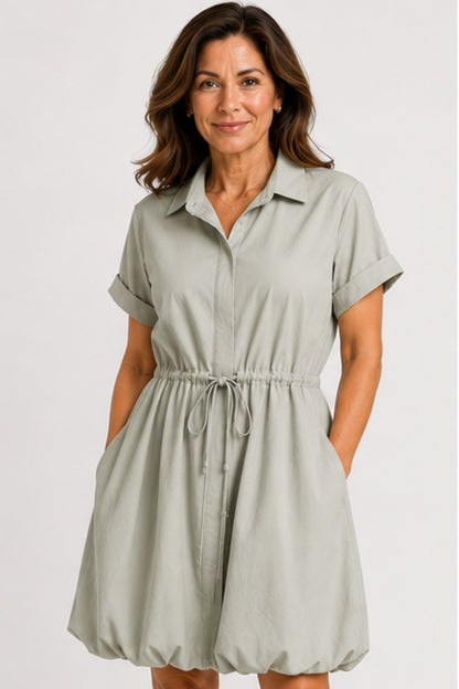 Mineral gray cinched shirt dress with button-front design, adjustable waist, roll-tab sleeves, and side pockets styled for elegant everyday wear.