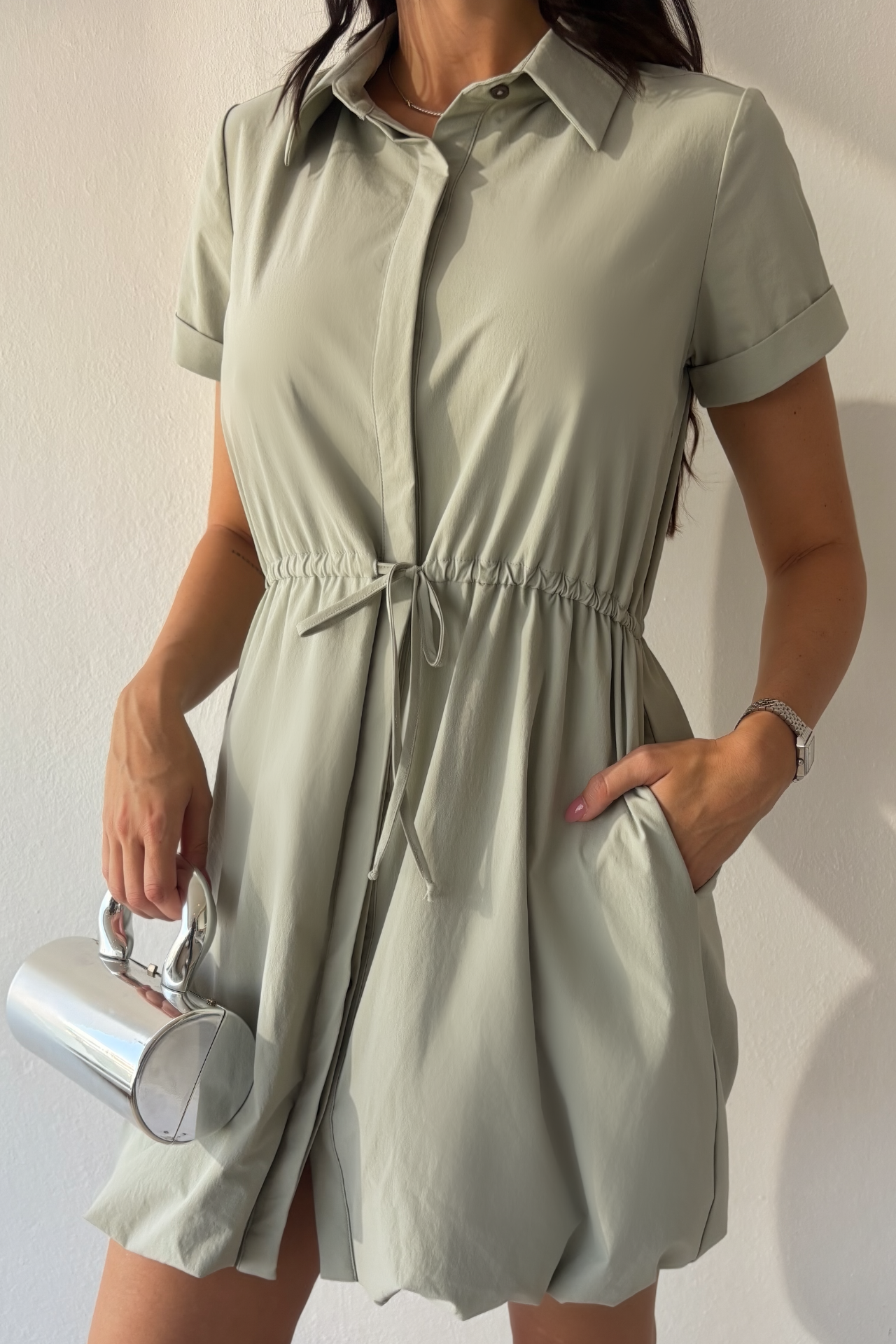 Mineral gray cinched shirt dress with button-front design, adjustable waist, roll-tab sleeves, and side pockets styled for elegant everyday wear.