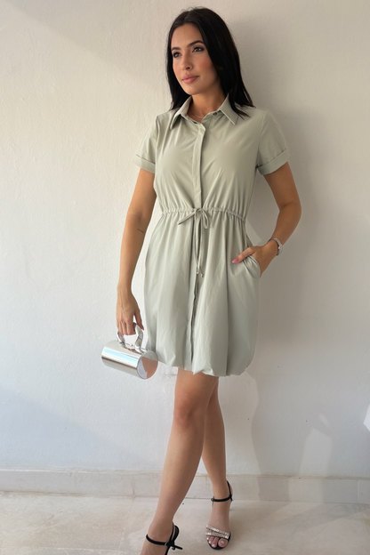 Mineral gray cinched shirt dress with button-front design, adjustable waist, roll-tab sleeves, and side pockets styled for elegant everyday wear.