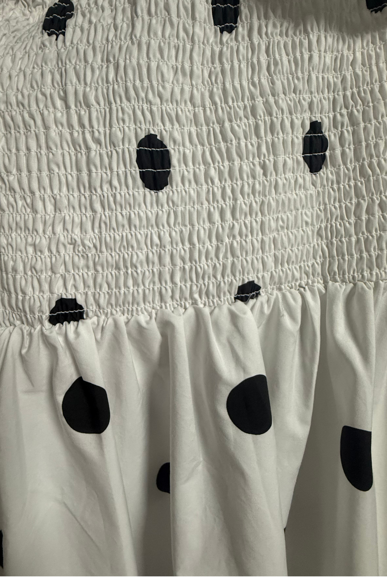 Close-up of Monroe Polka Dress showing black polka dot cotton fabric and smocked elastic detailing