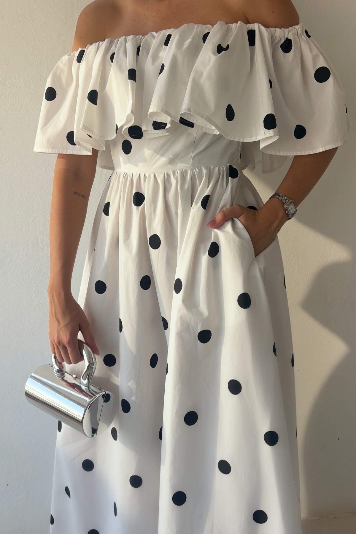 Monroe Polka Dress in white cotton with black polka dots, off-the-shoulder ruffle neckline and maxi silhouette