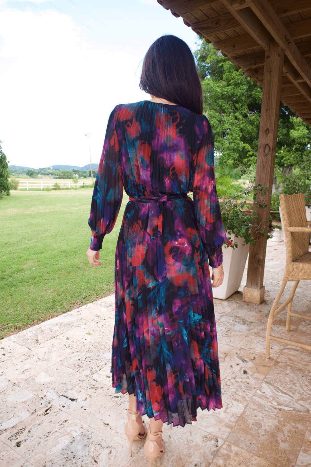 A woman wearing a long sleeve V-neck multicolor plisse dress, standing outdoors.