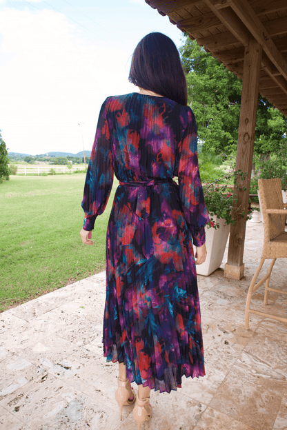 A woman wearing a long sleeve V-neck multicolor plisse dress, standing outdoors.