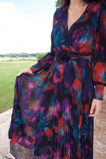 A woman wearing a long sleeve V-neck multicolor plisse dress, standing outdoors.