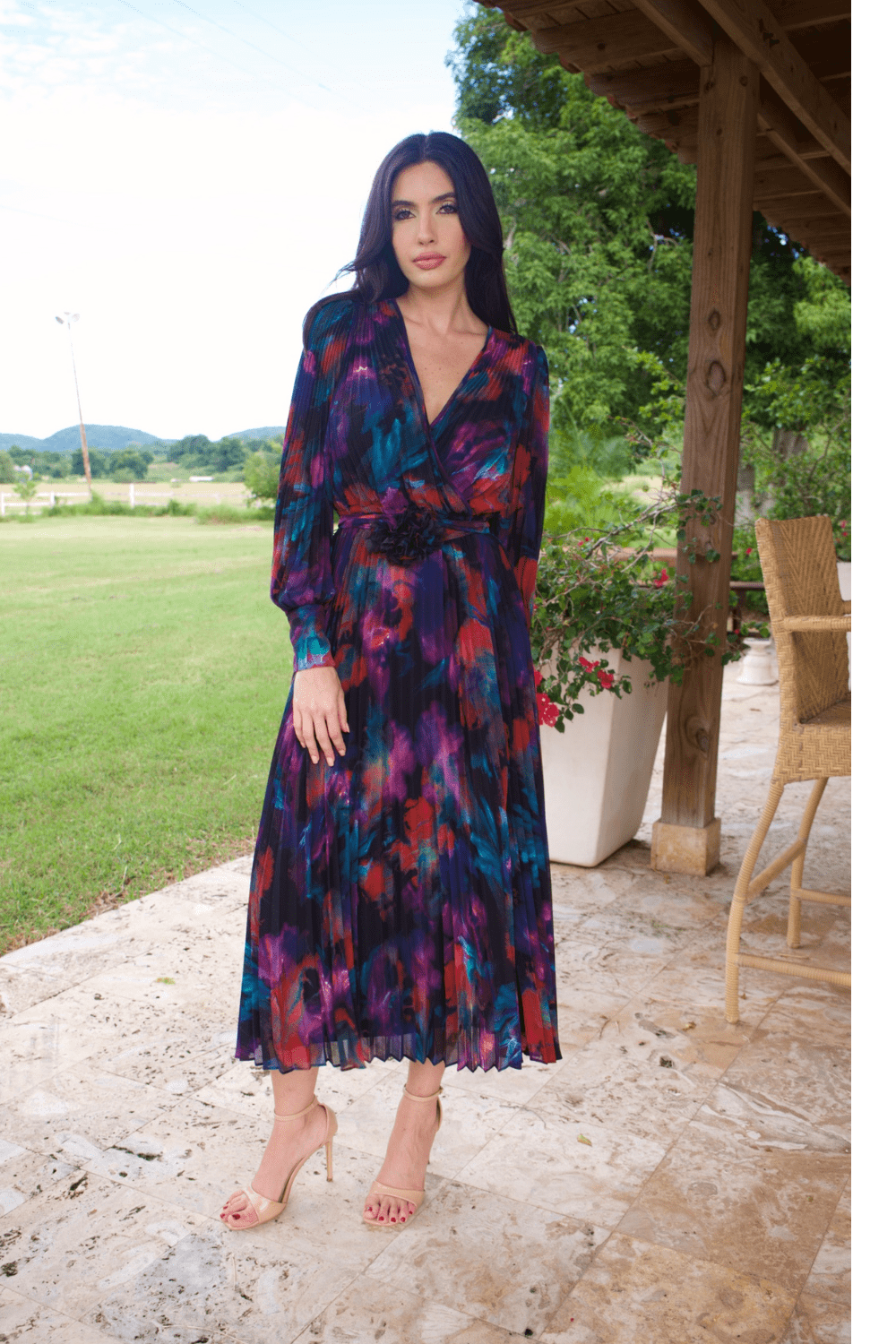 A woman wearing a long sleeve V-neck multicolor plisse dress, standing outdoors.