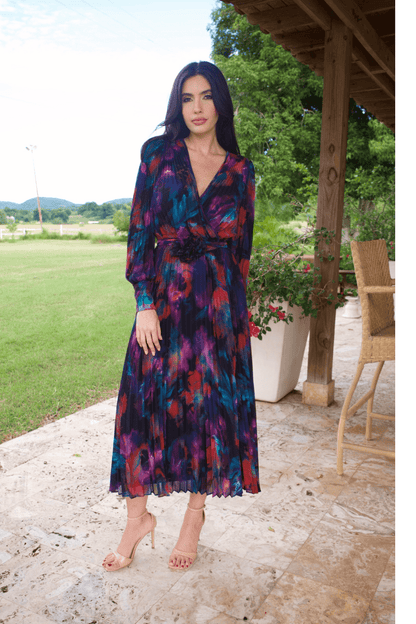 A woman wearing a long sleeve V-neck multicolor plisse dress, standing outdoors.