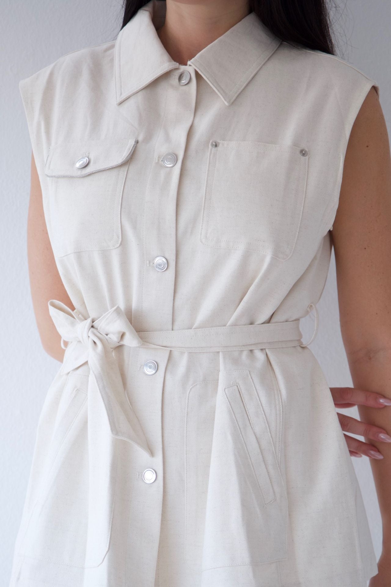 Natural sleeveless vest with buttons on a plain background