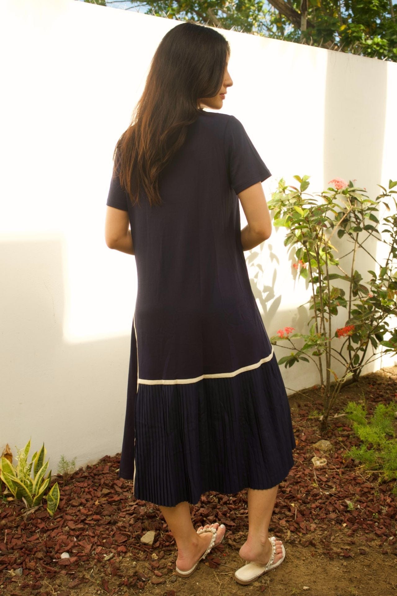 Back view of navy sleeveless maxi dress with soft pleats and clean lines.

