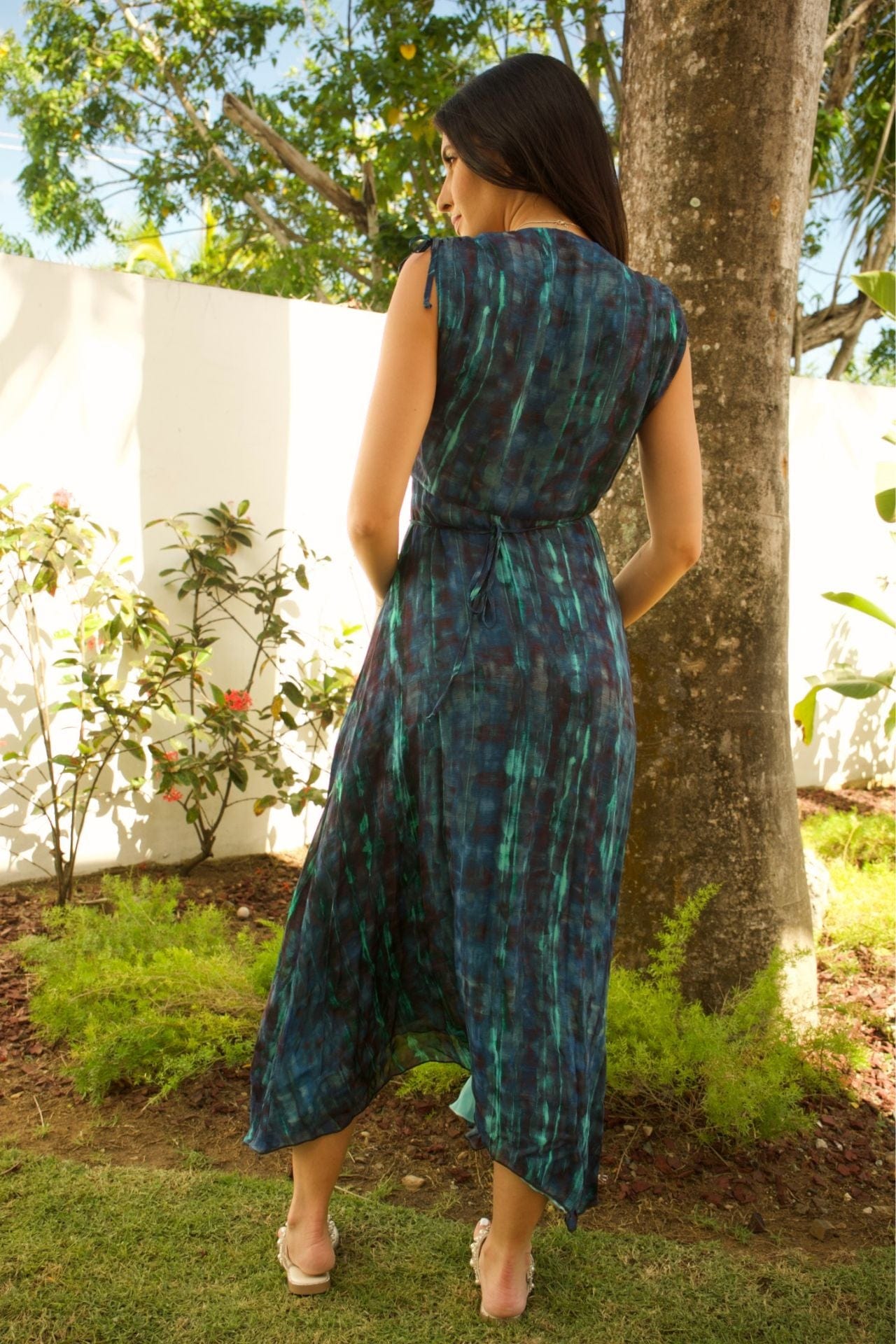 Back view of sleeveless maxi dress with tie waist and flowing hem.