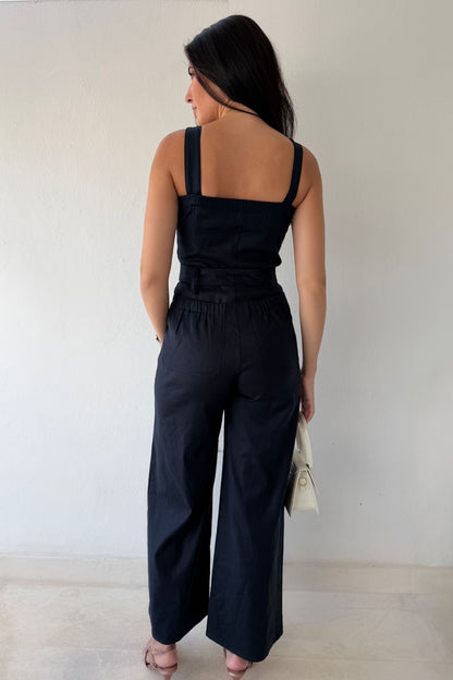 Model wearing the Navy Harbor Jumpsuit featuring a square neckline, self-tie waist, and wide-leg silhouette in navy.